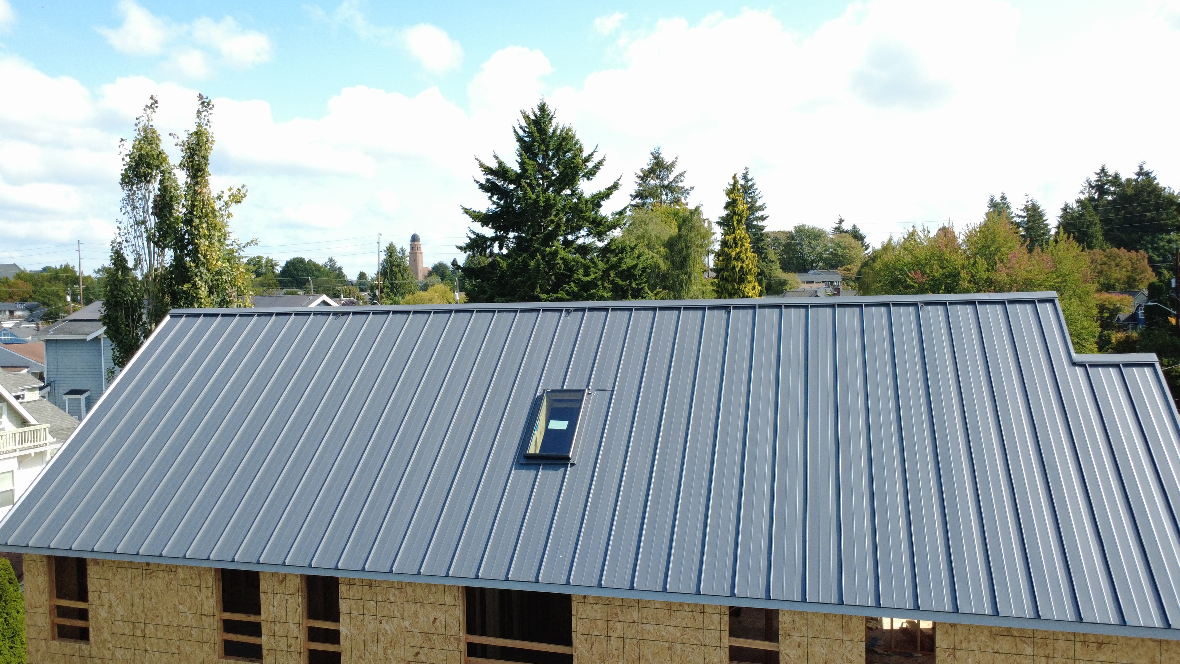 Close-up drone view of standing seam metal roof panels with integrated skylight