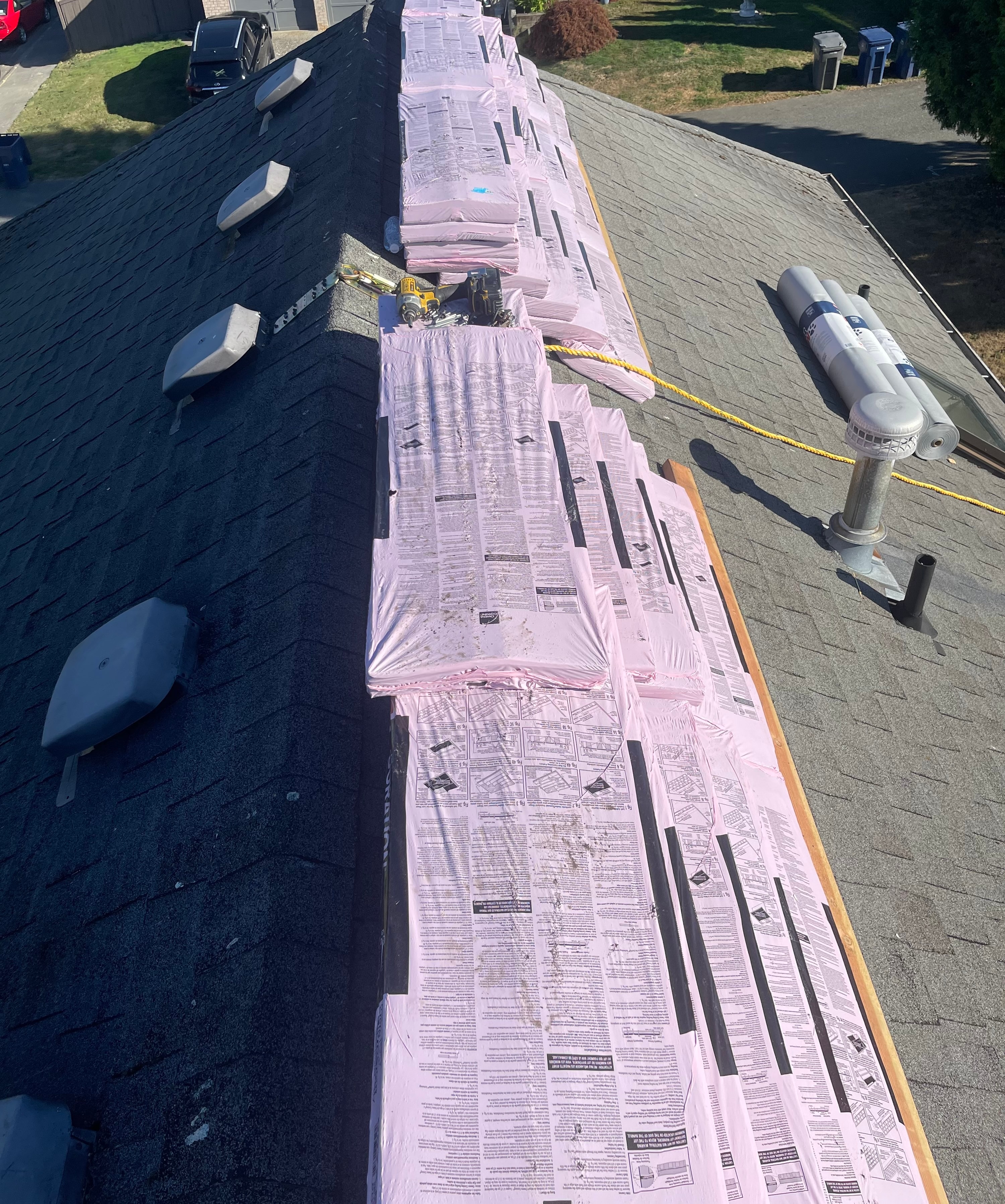 Aerial view of residential roof with new shingle bundles staged along the ridge during installation